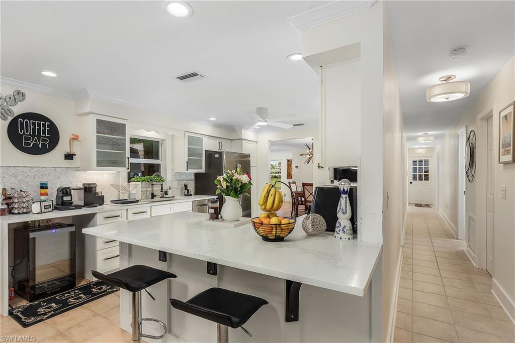2950 Coach House Lane Naples, FL 34105 - Photo 24 of 50 a kitchen with a sink a refrigerator and chairs