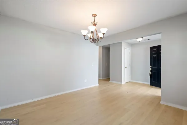 a view of an empty room with chandelier fan