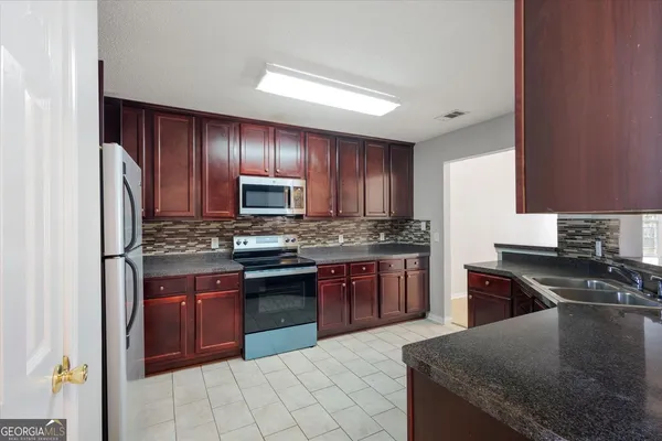 a kitchen with stainless steel appliances granite countertop a stove a sink dishwasher a refrigerator and a microwave oven