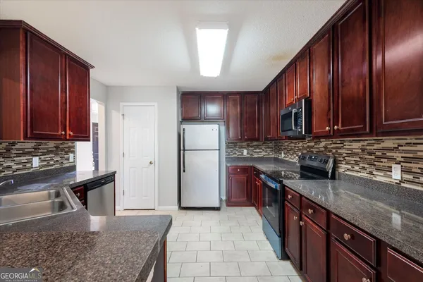 a kitchen with stainless steel appliances granite countertop wooden cabinets a sink dishwasher a refrigerator and a stove