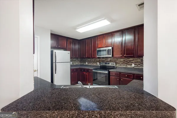 a kitchen with stainless steel appliances granite countertop a refrigerator stove and sink