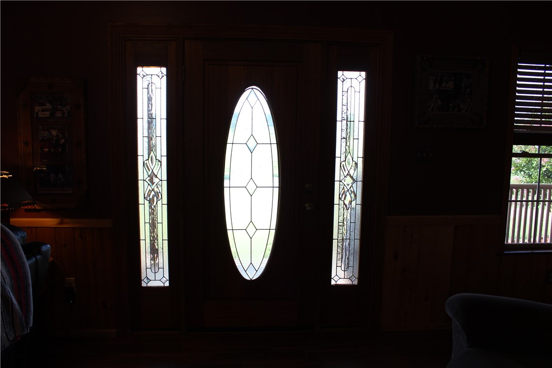 2210 Weiterer Road Scranton, AR 72863 - Photo 23 of 49 Dark wood-finish entry door with an oval-shaped decorative glass insert, flanked by two vertical decorative glass sidelights