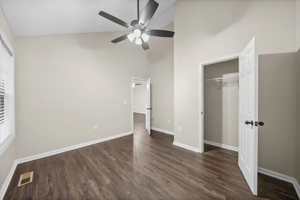 an empty room with wooden floor and a ceiling fan