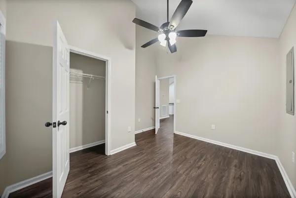an empty room with wooden floor closet and windows