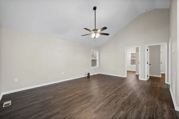 a view of an empty room with a window and wooden floor