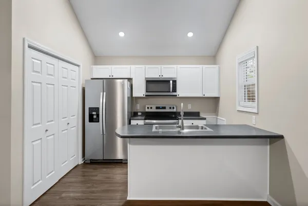 a kitchen with stainless steel appliances granite countertop a refrigerator a stove a sink and a microwave