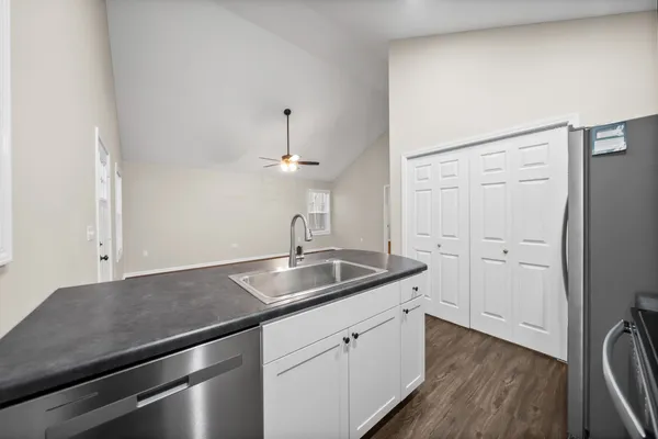 a kitchen with a sink dishwasher and white cabinets with wooden floor