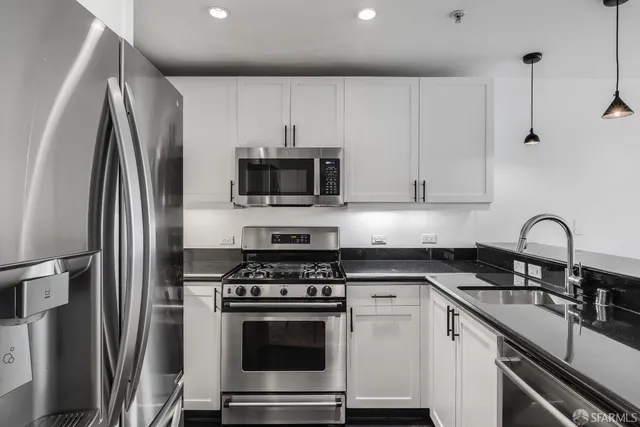 a kitchen with stainless steel appliances a sink a stove a refrigerator and cabinets