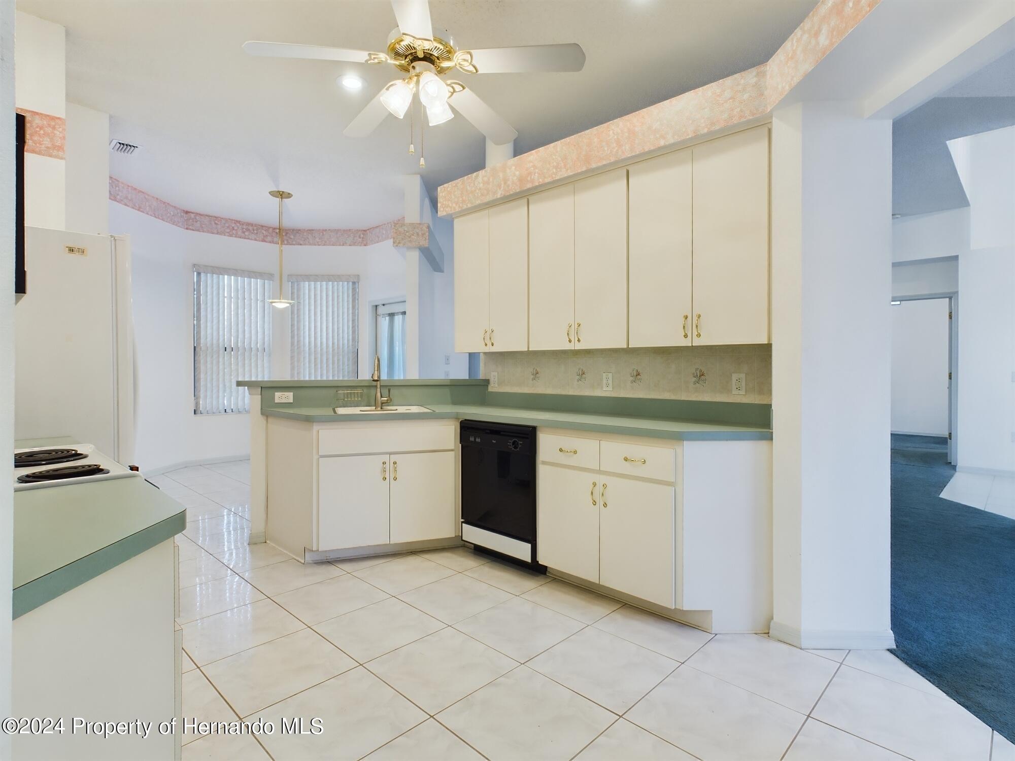 9198 Elida Road Spring Hill, FL 34608 - Photo 8 of 40 a kitchen with granite countertop white cabinets and white appliances