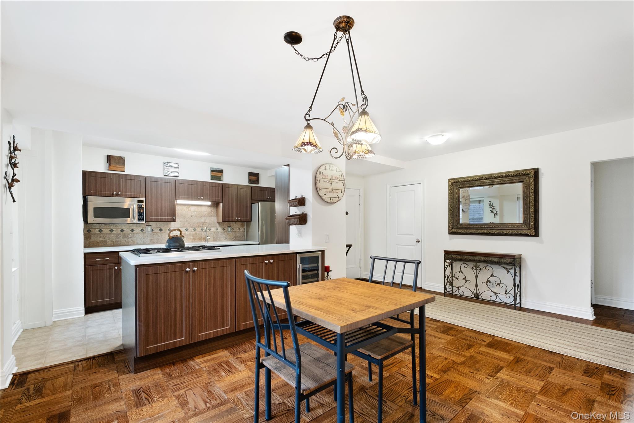 235 Garth Road, Unit E2A Scarsdale, NY 10583 - Photo 5 of 37 a dining room with stainless steel appliances granite countertop a stove top oven a sink dishwasher and a dining table with wooden floor