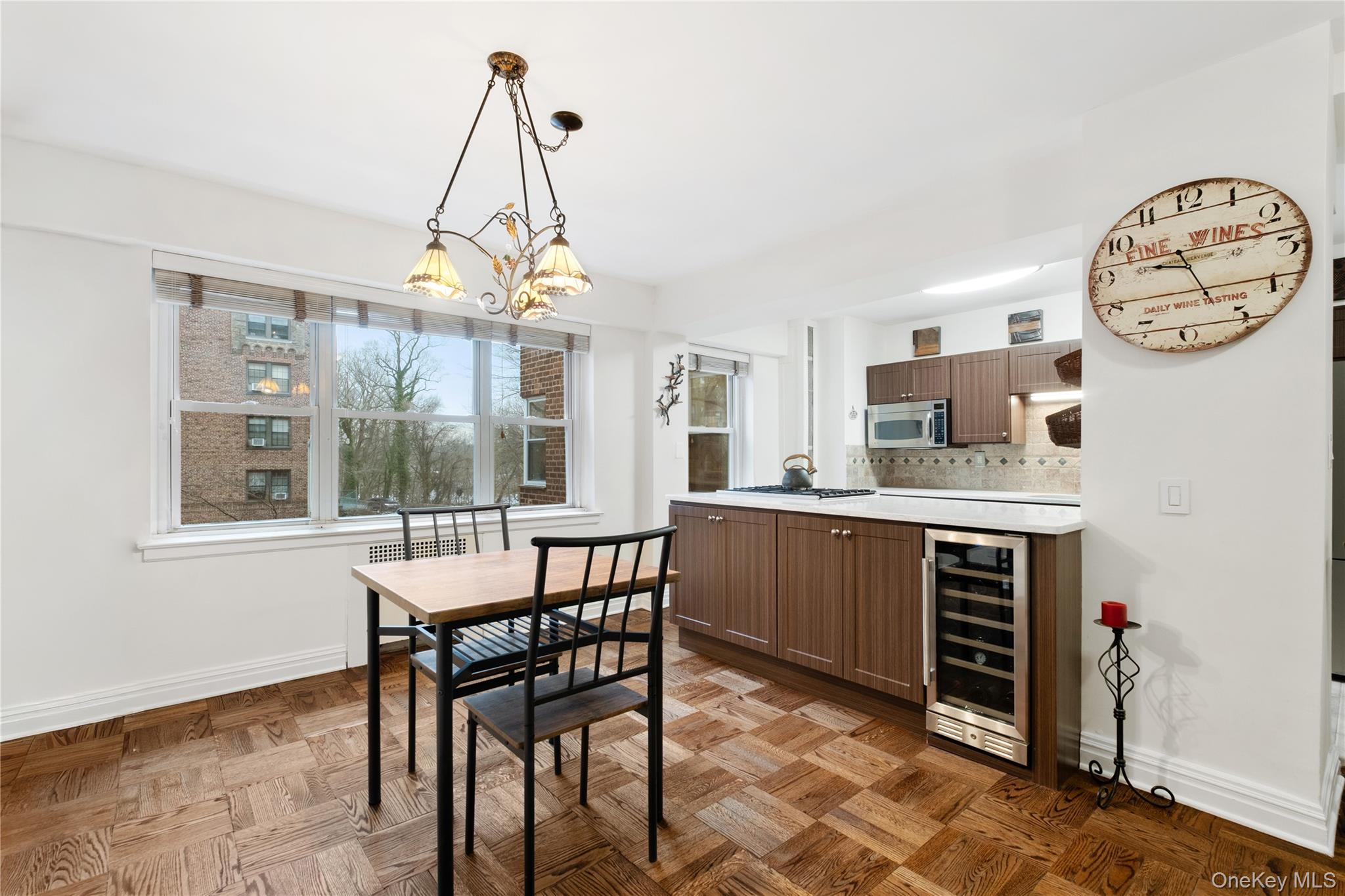 235 Garth Road, Unit E2A Scarsdale, NY 10583 - Photo 7 of 37 a dining room with wooden floor a chandelier a wooden table and chairs