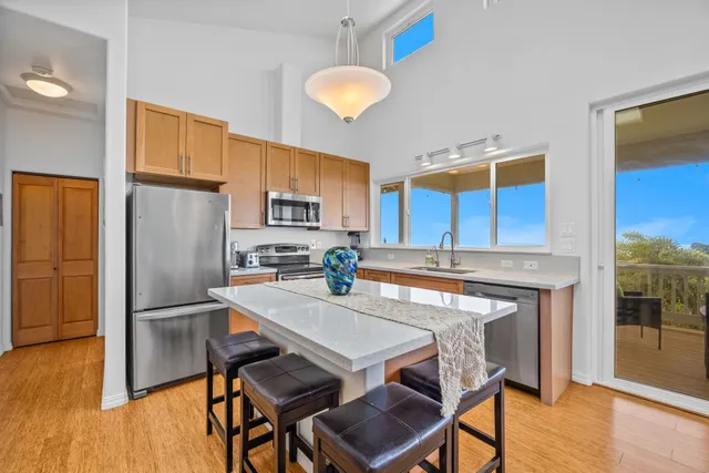 a kitchen with stainless steel appliances granite countertop a dining table chairs refrigerator and sink
