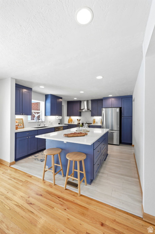 1180 North 400 East Bountiful, UT 84010 - Photo 18 of 50 Spacious kitchen featuring a central island with white countertop, extensive blue cabinetry, stainless steel appliances, and a combination of wood and wood-finish flooring