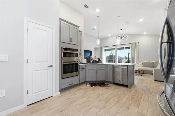 a large white kitchen with a refrigerator a stove a sink dishwasher with a fireplace and wooden floor