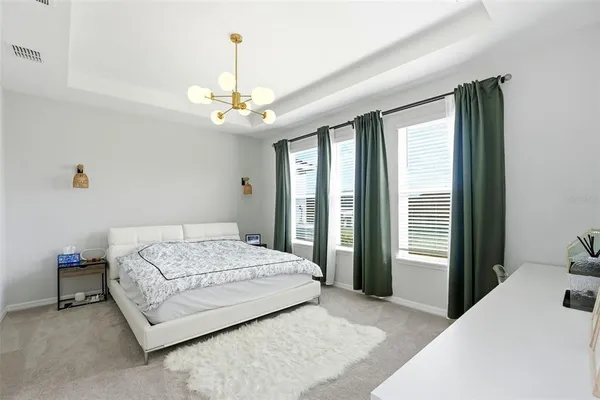 a bedroom with a large bed chandelier and a window