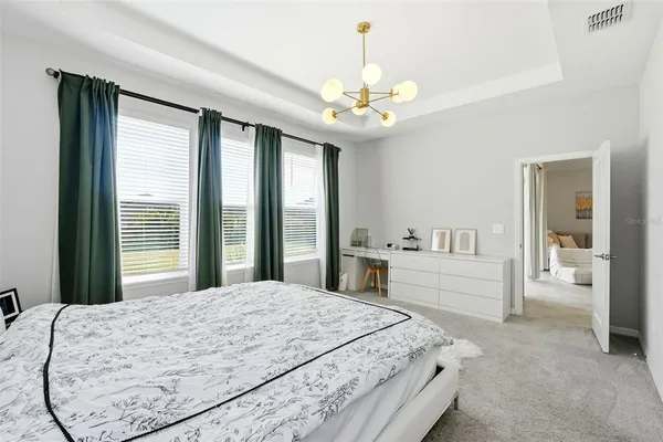 a spacious bedroom with a large bed and a chandelier