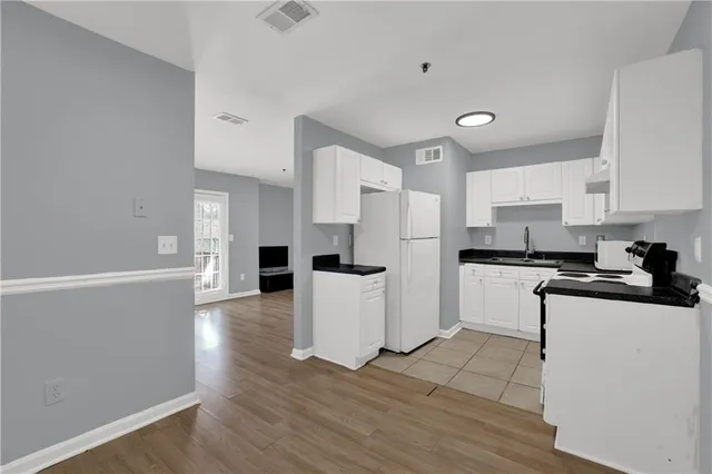 a kitchen with a refrigerator a stove top oven and white cabinets