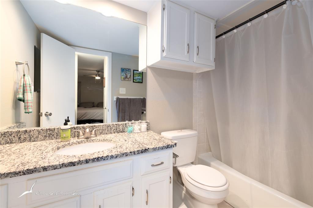 1318 Westheimer Road, Unit 217 Abilene, TX 79601 - Photo 14 of 16 a bathroom with a granite countertop sink toilet mirror and a shower