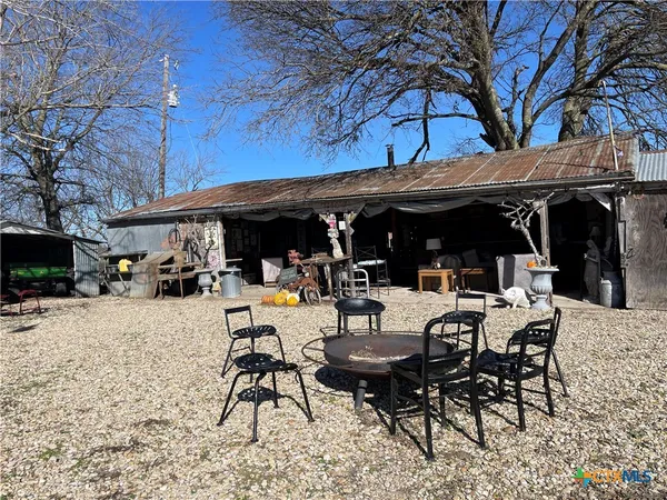 a view of a patio with table and chairs under an umbrella with barbeque grill and large trees