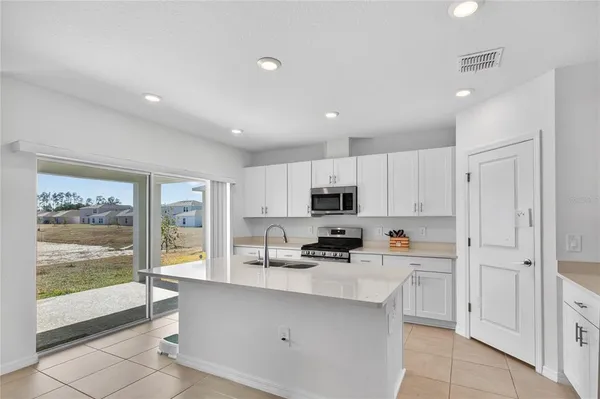 a kitchen with stainless steel appliances a sink a stove a refrigerator cabinets and a window