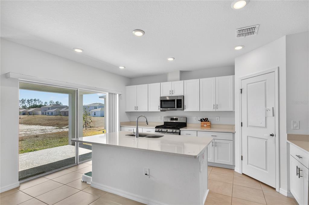 9633 Rampart Road Leesburg, FL 34788 - Photo 4 of 34 a kitchen with stainless steel appliances a sink a stove a refrigerator cabinets and a window