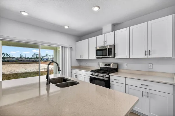 a kitchen with granite countertop a stove a sink and a microwave