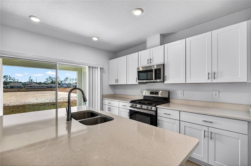 9633 Rampart Road Leesburg, FL 34788 - Photo 6 of 34 a kitchen with granite countertop a stove a sink and a microwave