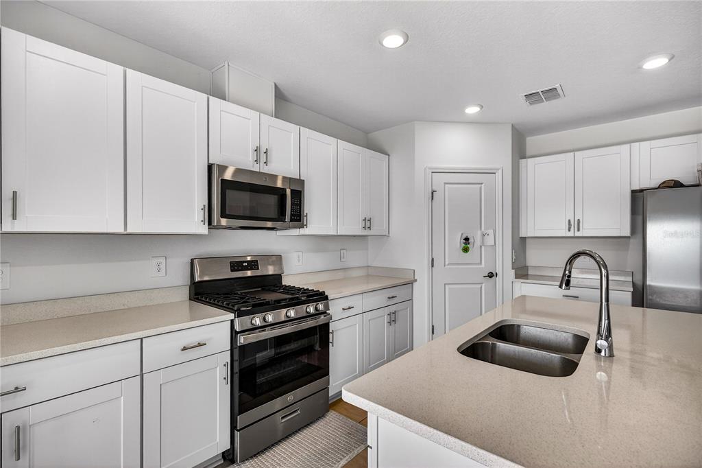 9633 Rampart Road Leesburg, FL 34788 - Photo 8 of 34 a kitchen with white cabinets and stainless steel appliances