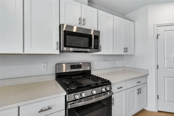 a kitchen with granite countertop white cabinets and stainless steel appliances