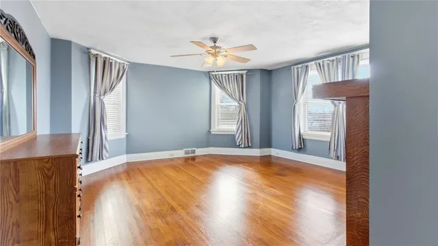 a view of an empty room with window and wooden floor