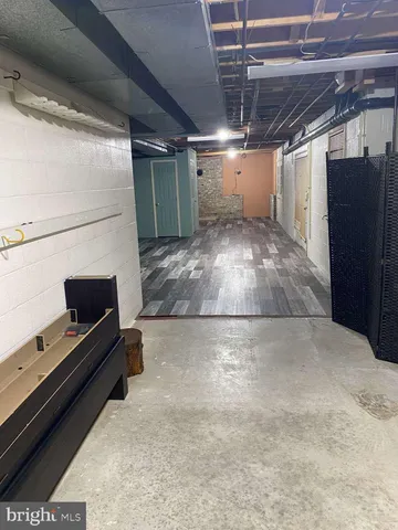 a view of an empty room with wooden floor and a kitchen
