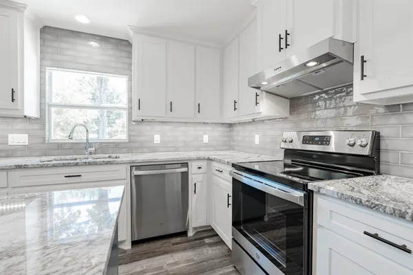 a kitchen with stainless steel appliances granite countertop a stove and a white cabinets