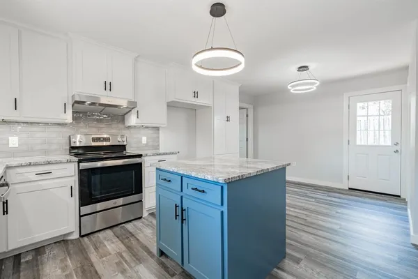 a kitchen with granite countertop a stove cabinets and wooden floor