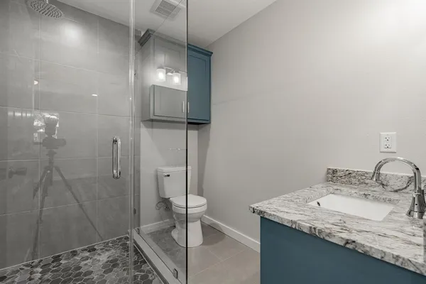 a bathroom with a granite countertop sink a toilet and shower