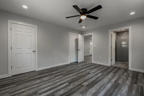 an empty room with wooden floor and a ceiling fan