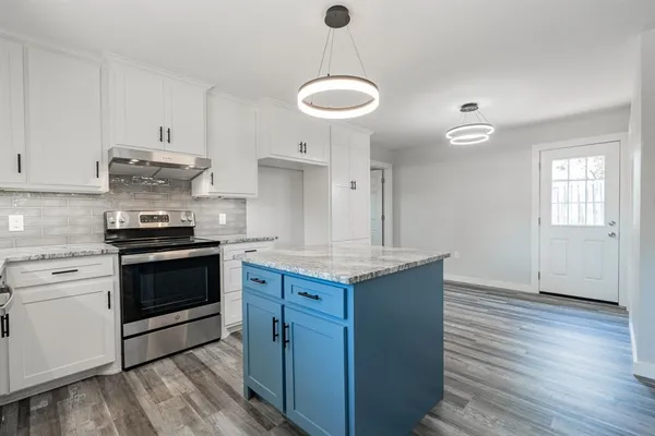 a kitchen with granite countertop a stove cabinets and wooden floor