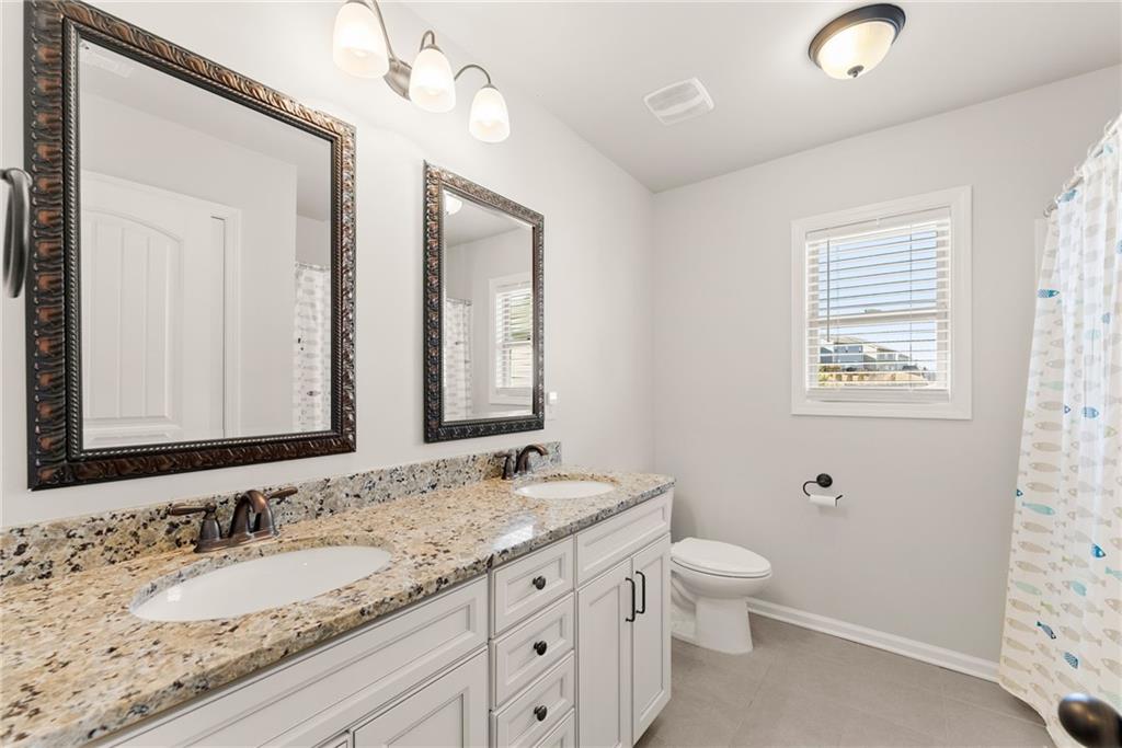 6667 Rivergreen Road Flowery Branch, GA 30542 - Photo 35 of 50 a bathroom with a granite countertop sink a toilet and a mirror