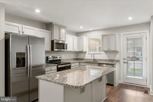 a kitchen with stainless steel appliances granite countertop a sink stove refrigerator and microwave