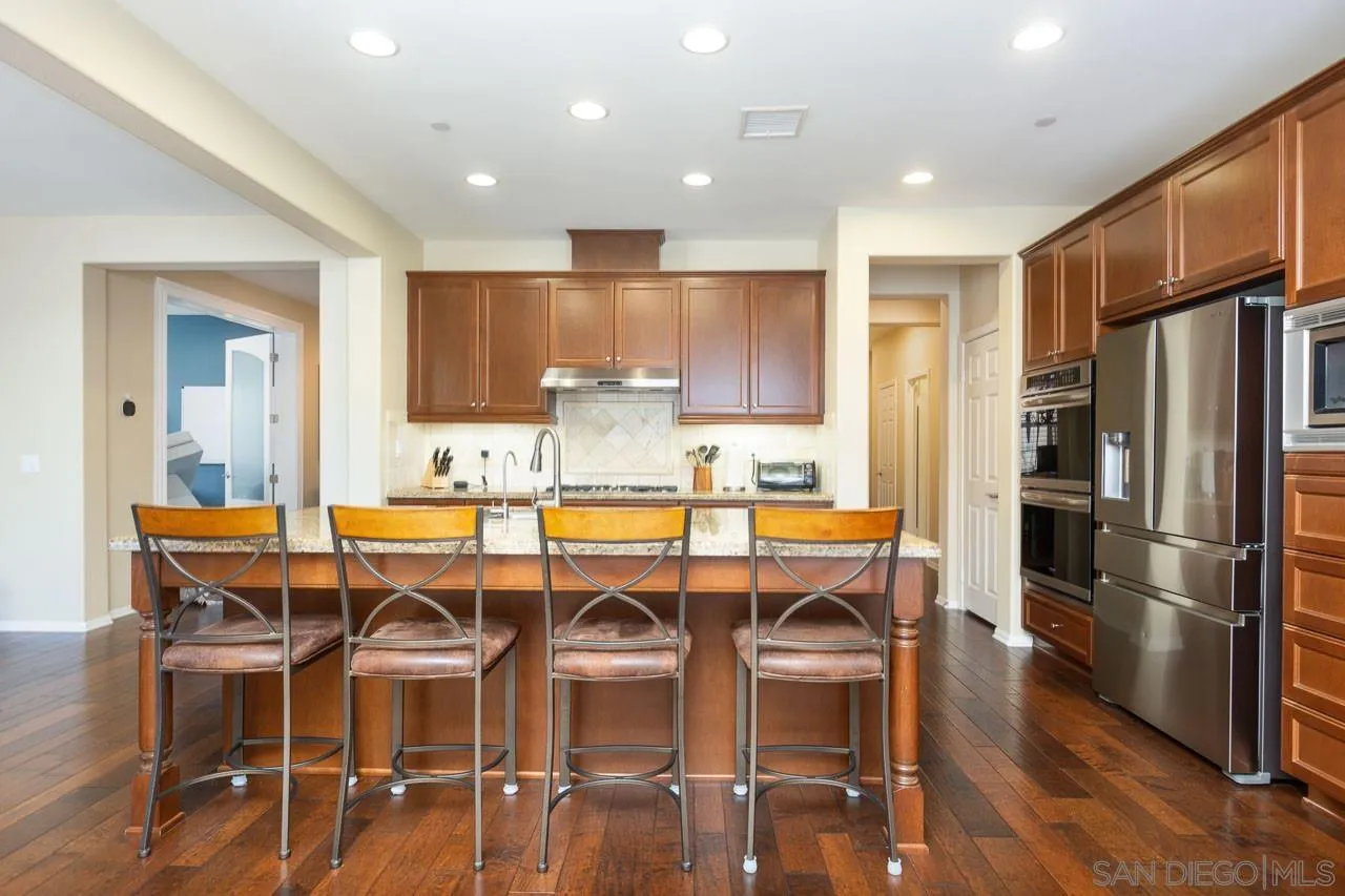17662 Ralphs Ranch Road San Diego, CA 92127 - Photo 6 of 27 a kitchen with stainless steel appliances granite countertop a dining table chairs refrigerator and sink