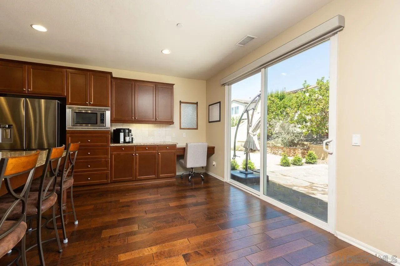 17662 Ralphs Ranch Road San Diego, CA 92127 - Photo 7 of 27 a kitchen with granite countertop a refrigerator and wooden floor