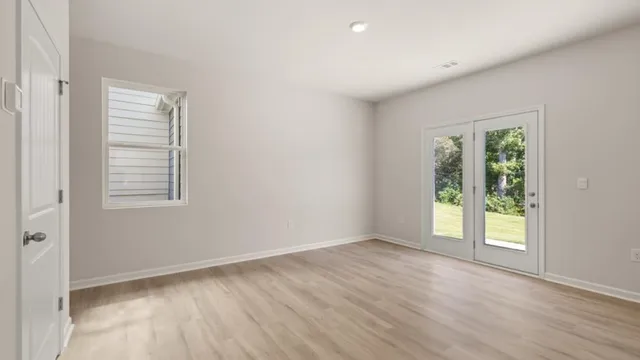 an empty room with wooden floor and windows