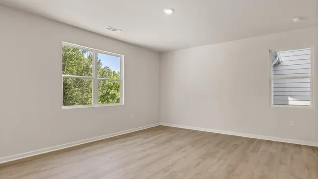 an empty room with wooden floor and windows