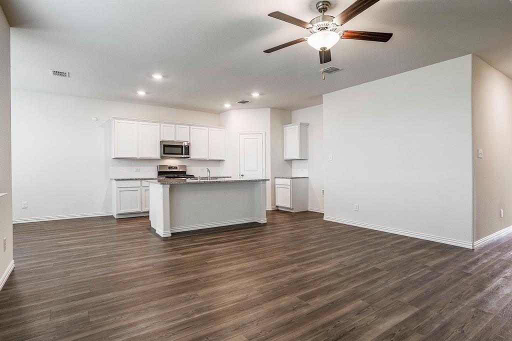 652 Ridgeback Trail Fort Worth, TX 76052 - Photo 7 of 20 Kitchen featuring dark hardwood / wood-style floors, an island with sink, white cabinets, light stone counters, and stainless steel appliances