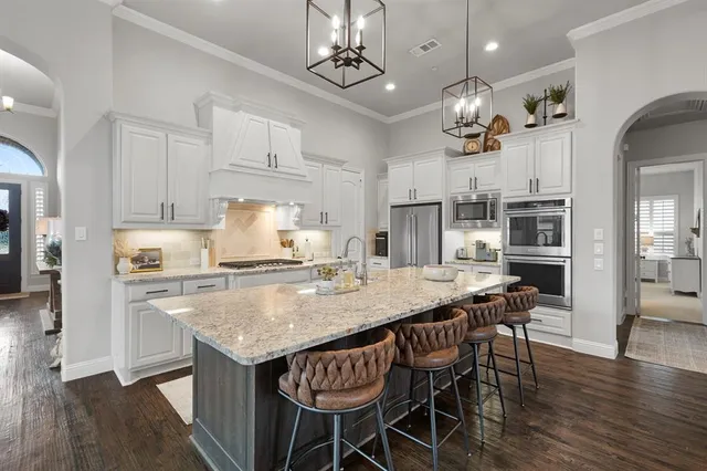 an open kitchen with granite countertop kitchen island stainless steel appliances a dining table and chairs