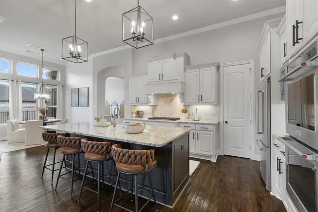 a kitchen with stainless steel appliances granite countertop a dining table chairs refrigerator and stove