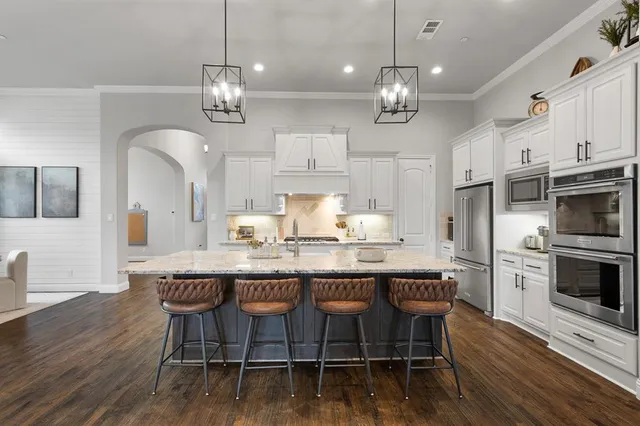 a kitchen with stainless steel appliances kitchen island granite countertop a wooden floor and white cabinets