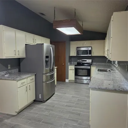 a kitchen with stainless steel appliances granite countertop a refrigerator a stove a sink and a microwave