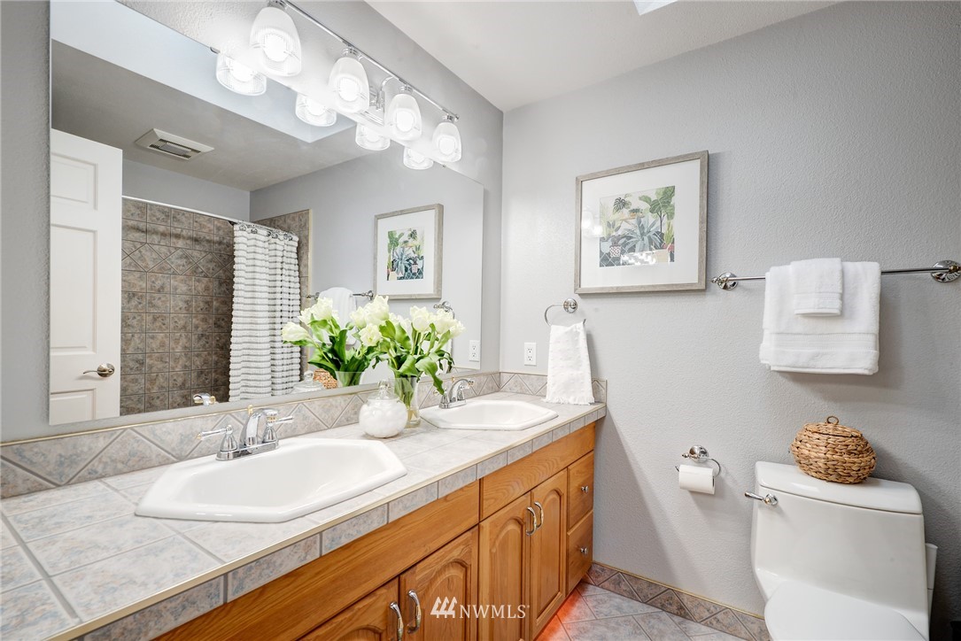 13621 196th Avenue Southeast Renton, WA 98059 - Photo 16 of 31 a bathroom with a granite countertop sink a large mirror a toilet and a shower