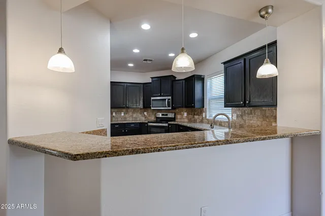 a large kitchen with granite countertop a stove top oven microwave and cabinets