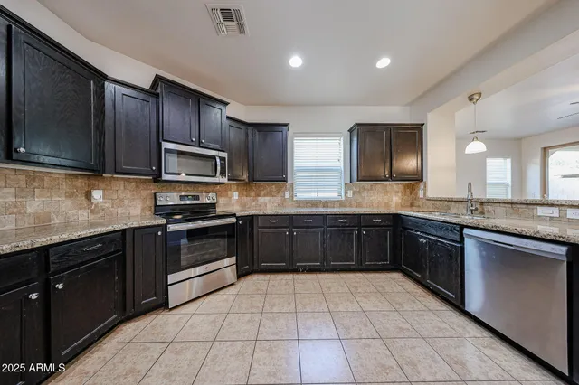 a kitchen with granite countertop wooden cabinets stainless steel appliances and a window
